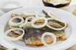 fried filet of sardines with onion on the plate