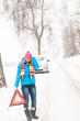 Woman with warning triangle car snow breakdown