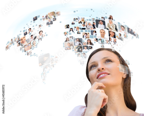 Photo: Young woman looking at worldmap with profile photos of her frien Young woman looking at worldmap with profile photos of her frien