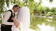 Ground married pair hugs and kisses under a large willow