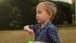 Handsome Little Boy winding kite rope on the green meadow