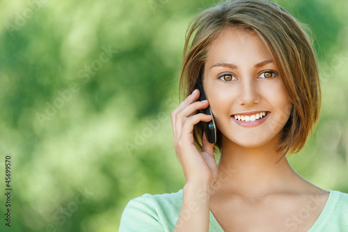 Photo: smiling beautiful young woman with phone smiling beautiful young woman with phone