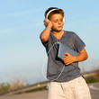 Boy enjoying music on tablet outdoors.