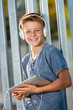 Cute teen boy holding tablet outdoors.