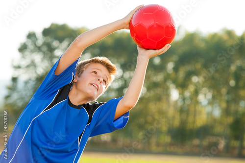 Photo: Young boy catching red ball outdoors. Young boy catching red ball outdoors.