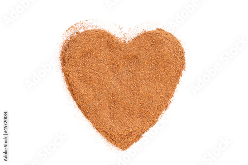 Photo: Heap of ground Cinnamon isolated in heart shape on white backgro Heap of ground Cinnamon isolated in heart shape on white backgro