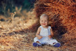 in a field near a haystack funny kid in blue suit