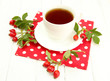 cup of tea with hip roses, on wooden table