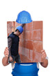 Builder hiding behind picture of construction site