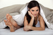 Annoyed woman in bed next to her partner's feet