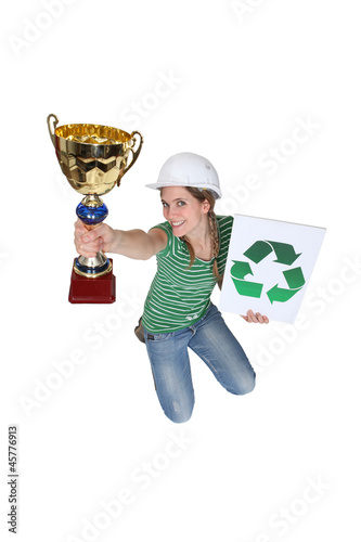 Photo: Woman jumping and holding a trophy and a recycle symbol Woman jumping and holding a trophy and a recycle symbol