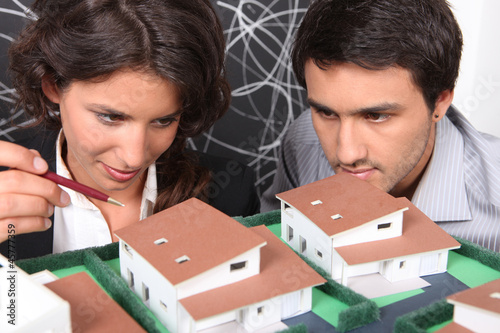 Photo: Two architect looking a miniature housing model Two architect looking a miniature housing model