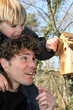 Father and son stood by bird-house