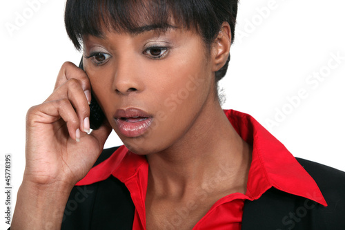 Photo: A black businesswoman getting bad news on the phone. A black businesswoman getting bad news on the phone.