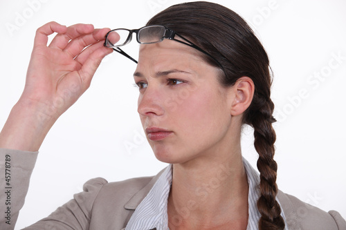 Photo: woman taking her glasses off to get a better look woman taking her glasses off to get a better look