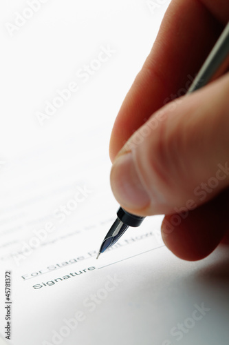 Photo: Closeup of a man holding a pen while doing document. Closeup of a man holding a pen while doing document.