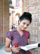 Young Indian college student reading a book in the campus.