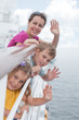 Mother with childrens stand on deck of ship and waving hands