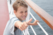 Little boy shows ok on deck of big passenger ship