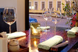 Table with glasses, candle, towels, sticks, with view on street