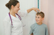 Doctor measures growth smiling boy in medical office