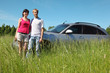 Husband, wife stand near car in field