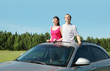 Husband, wife stand in hatch of car in field