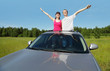 Husband, wife pose in hatch of car before hood in field