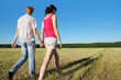 Happy husband, wife hold walk in field near wood, side