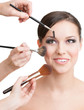 Photo: Three hands of makeup artists applying cosmetics Three hands of makeup artists applying cosmetics