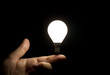 Lit light bulb balancing on finger
