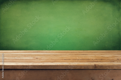 Wooden deck tabletop with grunge green wall