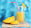 Ripe appetizing mango on woven napkin on blue background