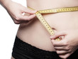 Young woman measures her waist circumference - isolated