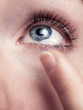Young woman with blue eyes uses contact lenses - isolated