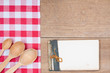 Red white tablecloth, spoons, old cookbook on wood background