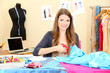 Photo: beautiful young dressmaker in workroom beautiful young dressmaker in workroom