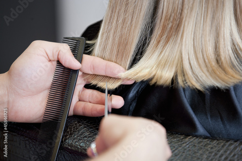 Photo: A male hairdresser cutting a young girls hair close up A male hairdresser cutting a young girls hair close up