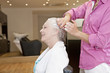 A male hairdresser applying product to womans hair, close up