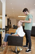 A male hairdresser applying product to his female clients hair