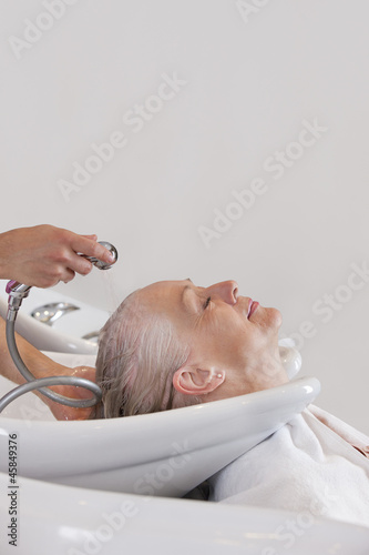 Photo: A senior woman having her hair washed at hairdressers, close up A senior woman having her hair washed at hairdressers, close up