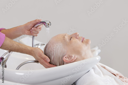 Photo: A senior woman having her hair washed at hairdressing salon A senior woman having her hair washed at hairdressing salon