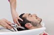 A male hairdresser washing a male clients hair, close up