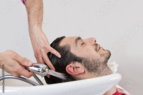 Photo: A male hairdresser washing a male clients hair, close up A male hairdresser washing a male clients hair, close up