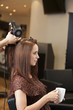 A male hairdresser blow drying a female clients hair