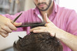 A hairdresser cutting man's hair with scissors, close up