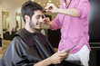 Man looking at a digital tablet whilst having his hair cut