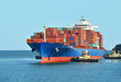 Tugboat assisting container cargo ship to harbor quayside
