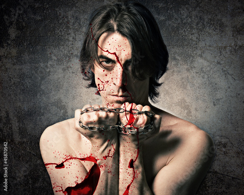 Photo: Terrible evil man with an iron chain and covered in blood. Terrible evil man with an iron chain and covered in blood.
