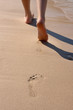 Photo: Details of legs of young woman walking through sand in the beach Details of legs of young woman walking through sand in the beach